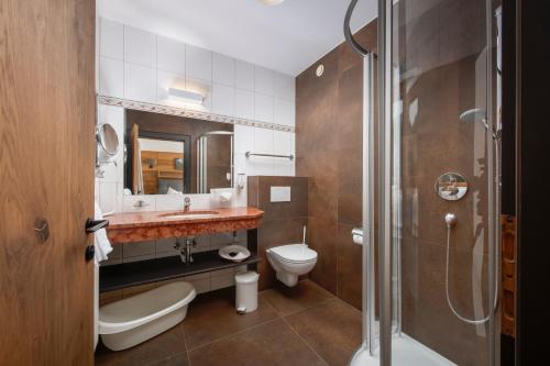 a bathroom with a toilet and a sink and a shower at Hotel Babymio in Kirchdorf in Tirol