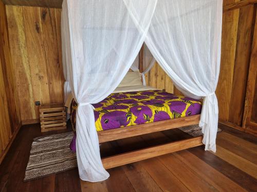 a bedroom with a bed with a mosquito net at CASE de ROBINSON in Lomé