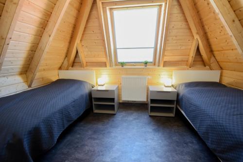 two beds in a attic room with a window at MP23 - Strandvogt 3 Komfort in Dorum Neufeld