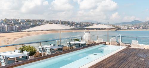 a swimming pool on top of a building with a beach at Lasala Plaza Hotel - Adults Only in Donostia-San Sebastián