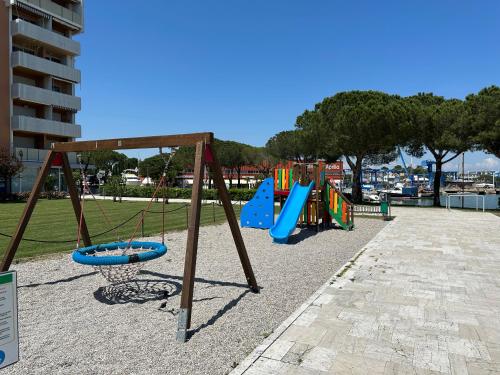 un parque infantil con columpios en Marina Bay View Apartment, en Bevazzana