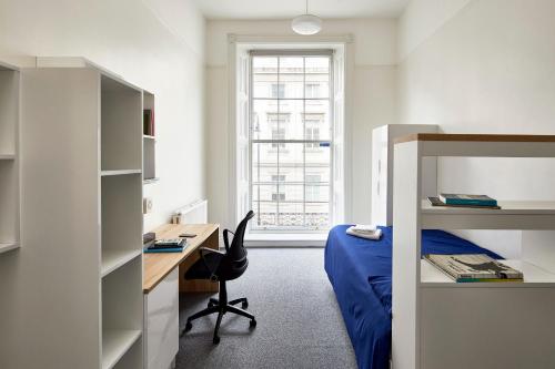 een slaapkamer met een bed, een bureau, een bed en een raam bij Gower Street Houses, Fitzrovia, London in Londen