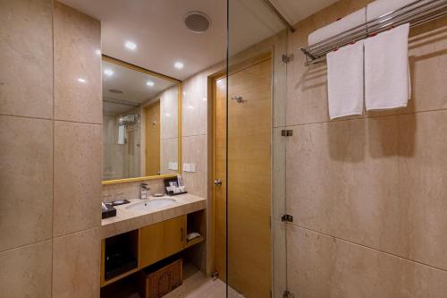 a bathroom with a sink and a shower with a mirror at Zone Connect by The Park Saket New Delhi in New Delhi