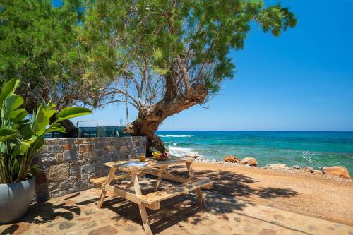 a picnic table on the beach near the ocean at Milatos Seaside Suites in Milatos
