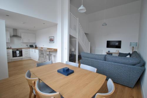 a living room with a wooden table and a couch at Walters Neuk Anstruther- luxury coastal home in Anstruther