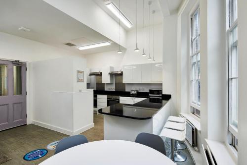 een keuken met witte kasten en een tafel en stoelen bij Gower Street Houses, Fitzrovia, London in Londen