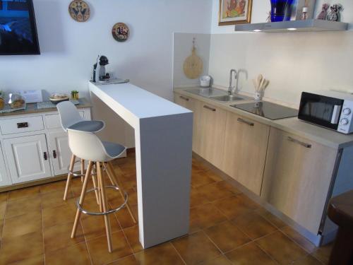 a kitchen with a counter with two chairs and a sink at Casa Vacanza LiHele - Locazione Turistica in Castelsardo