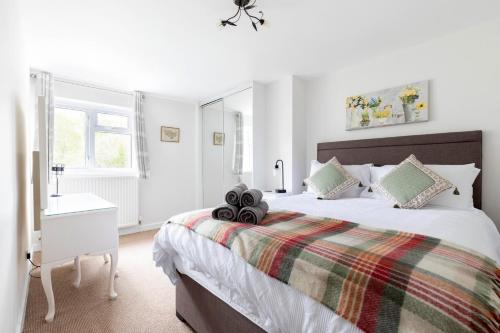 a white bedroom with a large bed and a window at Luxury Cheltenham Home with EV charger - Lechampton Hills in Cheltenham