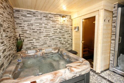 eine große Badewanne in einem Zimmer mit Ziegelwand in der Unterkunft Penzion Letohrádek in Frýdlant nad Ostravicí