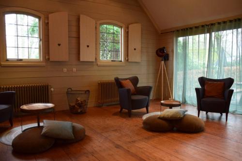 a living room with chairs and tables and windows at Villa de Beyaerd in Hulshorst