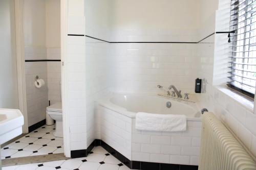 een witte badkamer met een bad en een toilet bij Villa de Beyaerd in Hulshorst