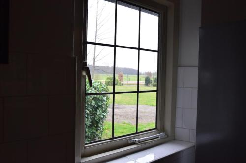 a window in a bathroom with a view of a field at Villa de Beyaerd in Hulshorst