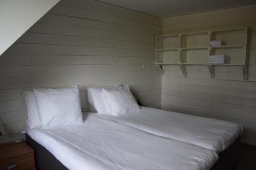 een bed met witte lakens en kussens in een kamer bij Villa de Beyaerd in Hulshorst
