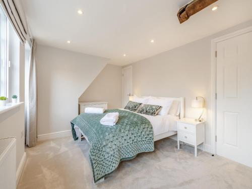a white bedroom with a bed with a green blanket at Gate House Apartment in Westerham