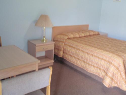 a hotel room with a bed and a desk and a table at Trans Canada Motel in Kamloops