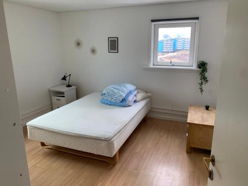 Habitación pequeña con cama y ventana en Dejlig og et godt hus, Hotel, en Sisimiut