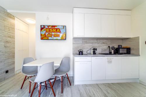 a kitchen with white cabinets and a white table and chairs at Wczasowa 8 Apartments in Sarbinowo