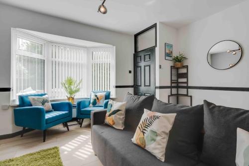 een woonkamer met een grijze bank en blauwe stoelen bij Orange Rentals- 3 bed Scouse House Sleeps up to 8 guests in Liverpool