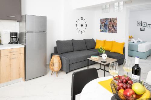 Athinais Suites في خيرسونيسوس: غرفة معيشة مع أريكة وطاولة مع وعاء من الفاكهة