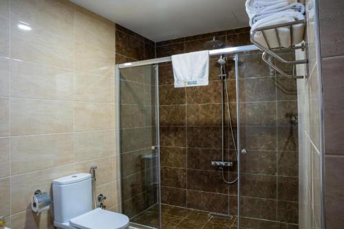 a bathroom with a shower with a toilet and a sink at Bloom Hotel in Baghdad