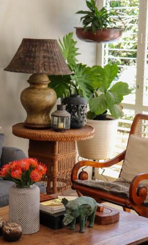 a living room with a table with a lamp and plants at Maison H Guest House in Durban