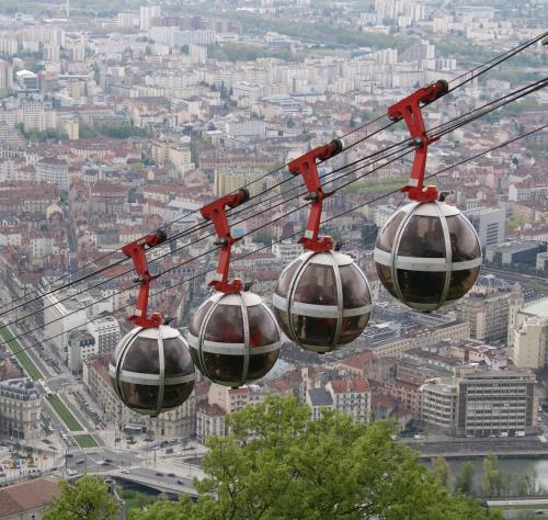 two gondolas on a ski lift over a city at Ekho Hotel Grenoble Nord Saint Egrève in Saint-Égrève