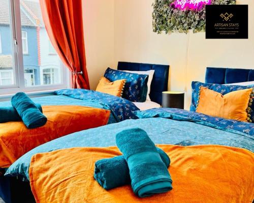 2 camas en una habitación con azul y naranja en Stunning Tropical Oasis By Artisan Stays I Free Parking I Long-stay Offer I Relocation or Business, en Southend-on-Sea