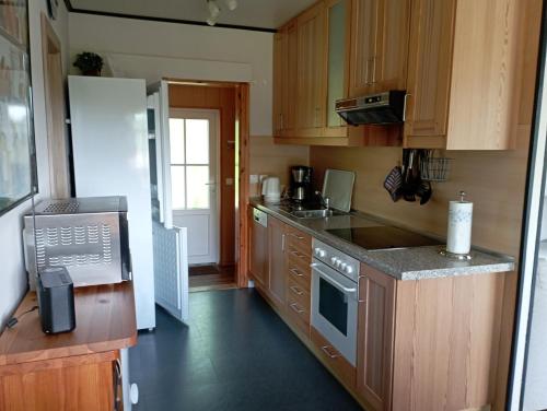 a kitchen with wooden cabinets and a white refrigerator at Ferienhaus "Op'n Barg" in Holzbunge