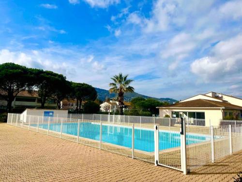 une clôture autour d'une piscine avec des arbres et une maison dans l'établissement T2 proche de la plage avec stationnement, à Mandelieu-la-Napoule