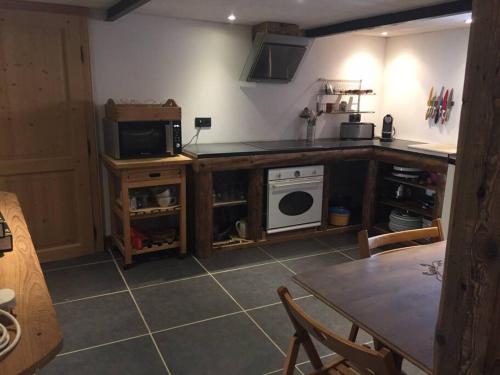 Il comprend une cuisine équipée d'une table, d'une cuisinière et d'un four micro-ondes. dans l'établissement Appartement une chambre dans ancienne ferme, à Passy