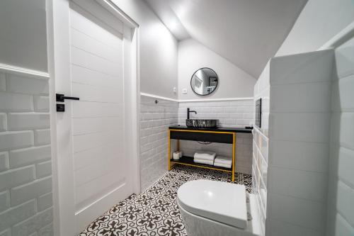 a white bathroom with a toilet and a sink at Zaspany Piec in Mikołajki