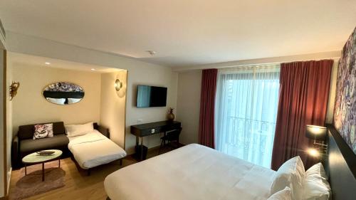 a hotel room with a bed and a couch at Hôtel La Villa Port d'Antibes & Spa in Antibes