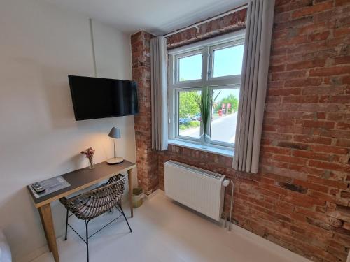 a room with a desk and a brick wall at Skovsgård Hotel in Brovst