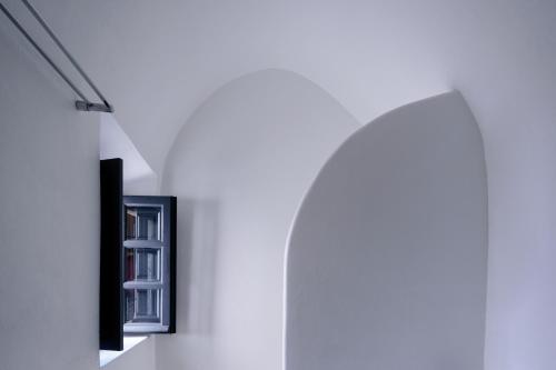 a room with a white wall with a book shelf at Firalia, Casa in Rock Suites in Fira