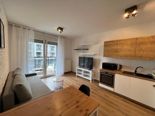 cocina y sala de estar con sofá y mesa en I&M Apartments Sikorskiego Wrocław, en Wroclaw