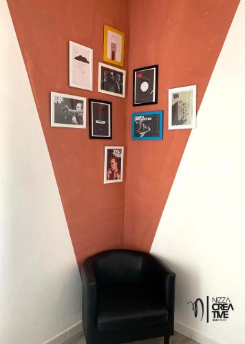 a room with a black chair and pictures on a wall at Hotel Nizza Creative Hotel in Rimini