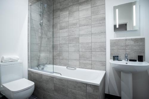 ein Badezimmer mit einer Badewanne, einem WC und einem Waschbecken in der Unterkunft Bayard Apartments -Two Bedroom Apartment - Contractors Welcome in Peterborough