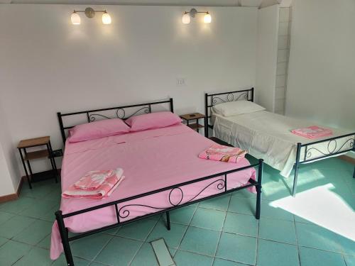 2 camas en una habitación con sábanas rosas en La Locanda, en Nociglia