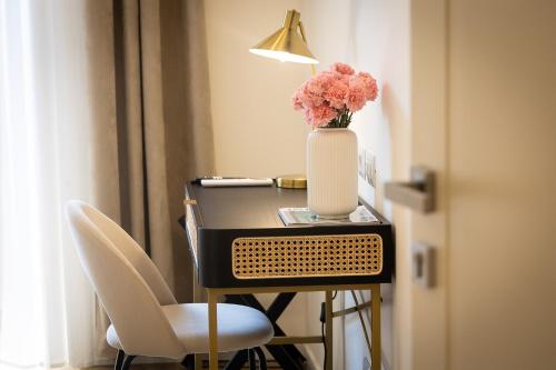 une table avec un vase de fleurs et une lampe dans l'établissement Colosseum Boutique Apartment, à Rome