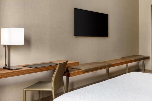a room with a desk and a television on a wall at AC Hotel by Marriott San Francisco Airport/Oyster Point Waterfront in South San Francisco