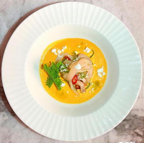 a white plate with a bowl of soup on a table at Adam Boutique Eilat in Eilat