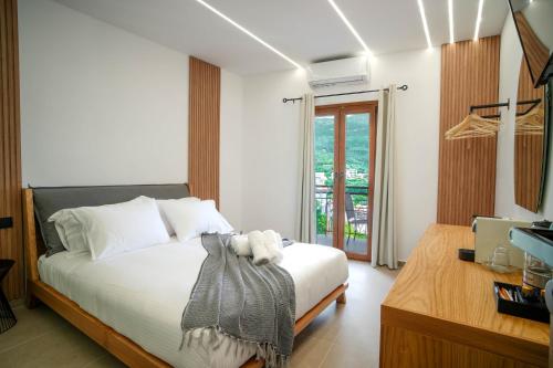 um quarto com uma cama com lençóis brancos e uma televisão em Omnia Deluxe Rooms em Parga