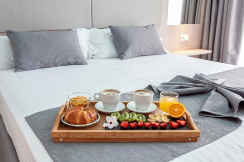 a tray of food on a bed with coffee and breakfast at Hospedium Hotel Abril in San Juan de Alicante
