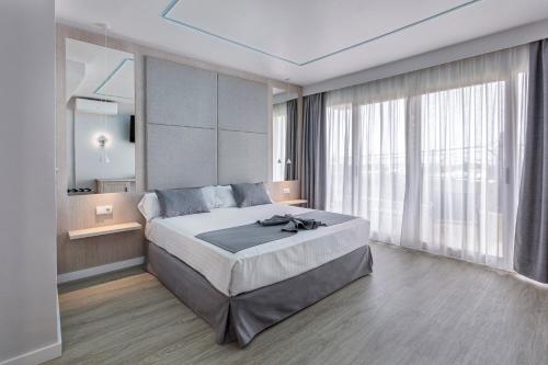 a bedroom with a large bed and a large window at Hospedium Hotel Abril in San Juan de Alicante