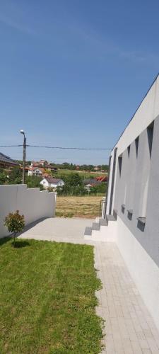 a white building with a sidewalk next to a field at Vila Andrea in Oradea