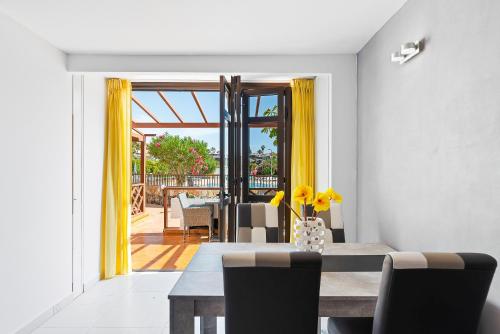 a dining room with a table and yellow curtains at Neptuno Pool and beach private access in Puerto de Santiago