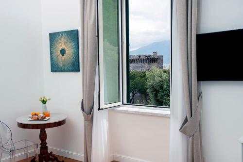 Relais al Castello في كاستيلاماري دي ستابيا: غرفة مع نافذة مع طاولة وطاولة صغيرة