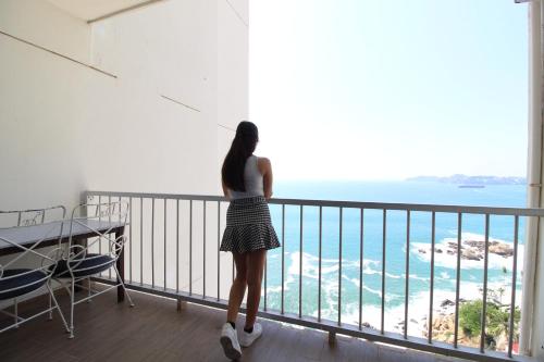 Una mujer parada en un balcón con vistas al océano en Las Torres Gemelas VIP, en Acapulco