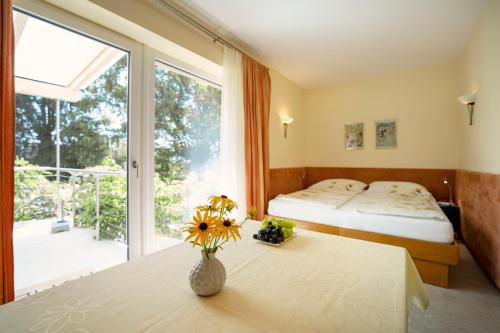Un dormitorio con 2 camas y una mesa con flores. en Apartments im Garten - Haus Daniela, en Graz