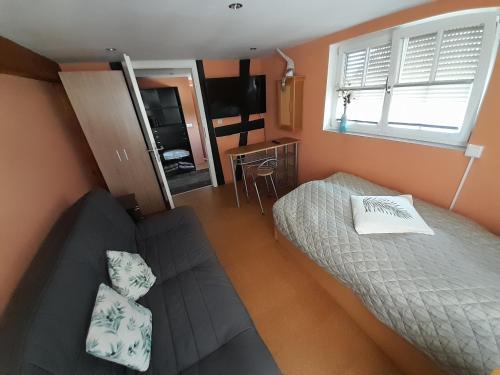 um pequeno quarto com uma cama e um sofá em Ferienwohnung Camino em Jockgrim